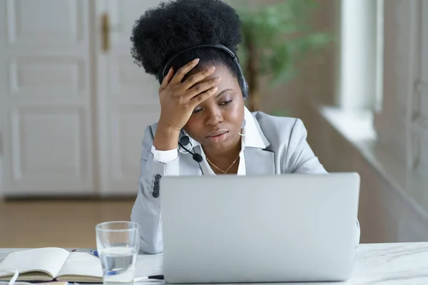 Fáradt afrikai női támogatás call center dolgozó headset frusztrált megjelenés ideges a laptop képernyőjén — Stock Fotó