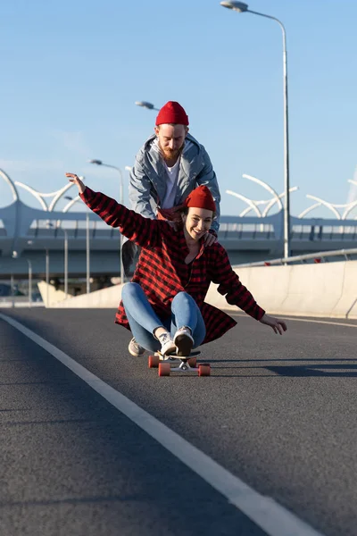Ευτυχισμένοι εραστές ζευγάρι ψύχρα σε εξωτερικούς χώρους βόλτα longboard, γέλιο και να διασκεδάσουν μαζί σε αστικό δρόμο της πόλης — Φωτογραφία Αρχείου