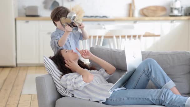 Μαμά ξαπλωμένη στον καναπέ με φορητό υπολογιστή εργασίας από το σπίτι ή να χαλαρώσετε με το παιδί προσχολικής ηλικίας κάνουν θορύβους αποσπά την προσοχή — Αρχείο Βίντεο