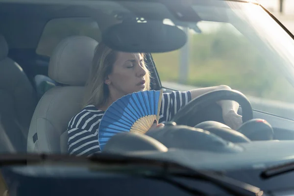 Conductor femenino con ventilador de mano que sufre de calor en el coche, tiene problemas con el aire acondicionado que no funciona — Foto de Stock