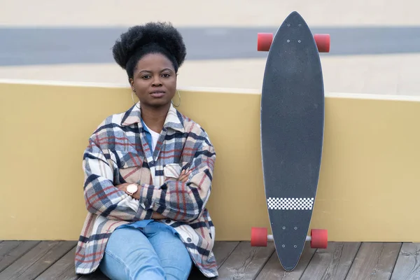 Νεαρή Αφρικανή γυναίκα χαλαρώστε μετά το skateboarding στο δρόμο της πόλης καθίσει ήρεμη συλλογίζεται. Αστικός τρόπος ζωής — Φωτογραφία Αρχείου