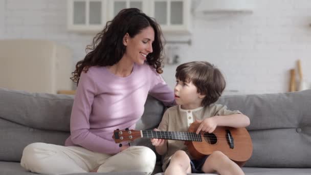 Happy mother spent time with child on weekend: mom teach preschool boy to play ukulele on lockdown — Stok Video