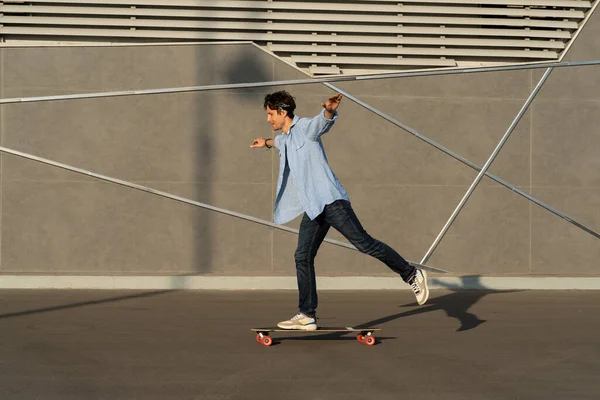 Молодий чоловік їде на дошці в міському вуличному скейтпарку. Випадковий хіпстер хлопець носить бандану скейтбординг — стокове фото