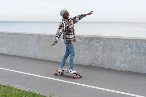 Ελευθερία και αστικός τρόπος ζωής: νεαρό κορίτσι skateboarding σε longboard στο δρόμο της πόλης ή κατάστρωμα κοντά στη θάλασσα — Φωτογραφία Αρχείου