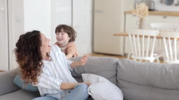 Schattige kleuterschool zoon en lachende moeder hebben grappig kussen gevecht genieten speelse indoor activiteit ontspannen — Stockvideo