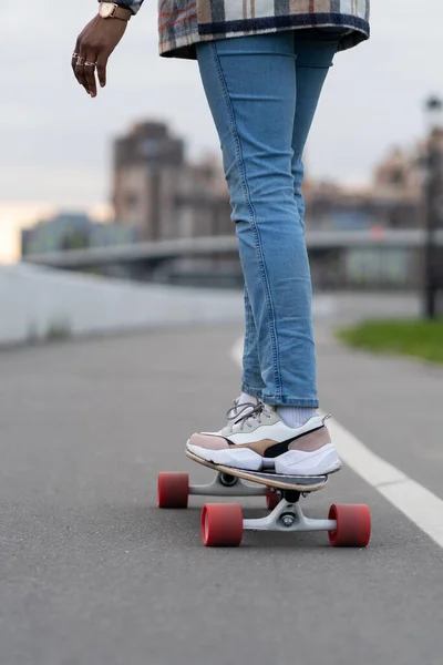 Mulher no longboard: imagem cortada de preto feminino desgaste tênis na moda sapatos e jeans no skate — Fotografia de Stock