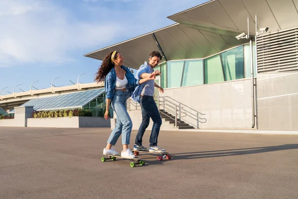 Χαρούμενο ζευγάρι σε ημερομηνία longboarding μαζί: hipster τύπος σκέιτερ διδάξει γέλιο γυναίκα βόλτα skateboard — Φωτογραφία Αρχείου