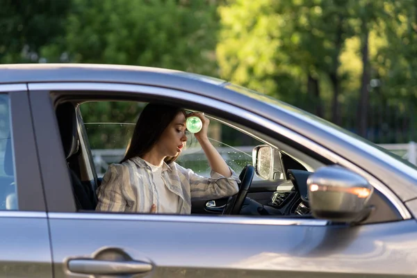 Вымотанная девушка водитель страдает от головной боли, жары, жаркая погода применяет бутылку воды на лоб — стоковое фото