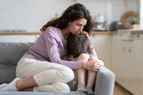 小さな男の子は母親の愛、保護とサポートを受けます。Mom cuddling son offended child cry on sofa — ストック写真