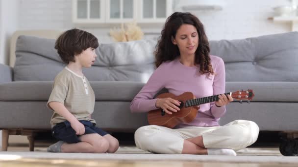 Mamma musicista godere di suonare la chitarra e cantare per il piccolo bambino in età prescolare annoiato a casa sul coronavirus blocco — Video Stock