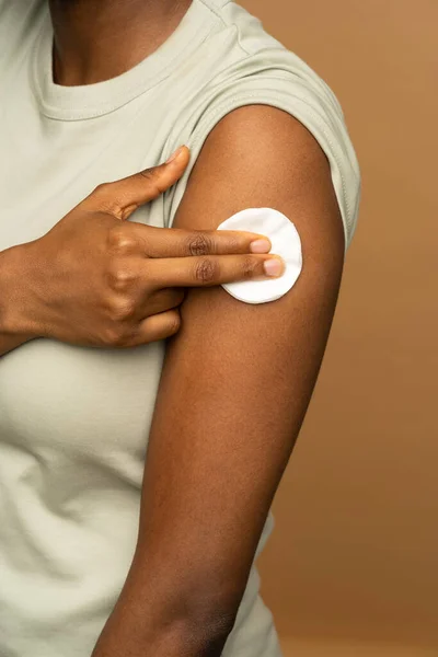 Чорна дівчина натискає пальці на бавовняну подушку на плечі після ін'єкції вакцини Ковід-19. Зачиніть.. — стокове фото