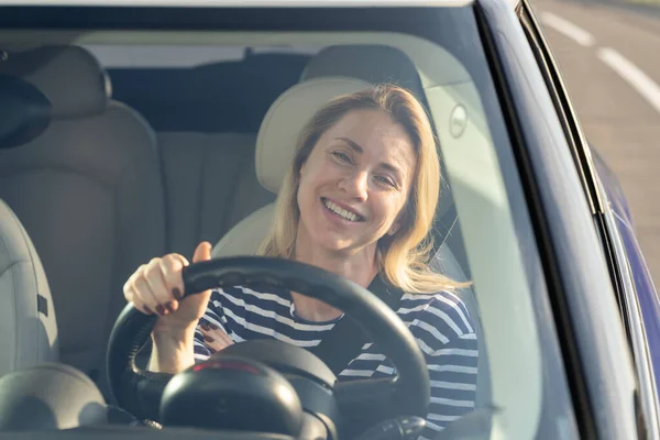 Счастливой женщине нравится водить новую машину. Возбужденная женщина-водитель в автомобильном настроении во время отпуска в дороге — стоковое фото