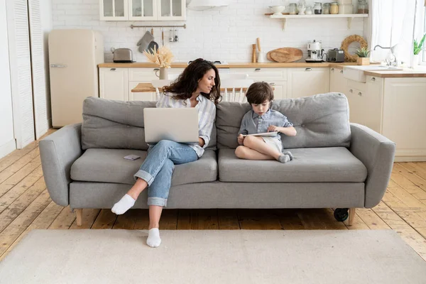 Werk vanuit huis bij Covid-19. Moeder zakenvrouw kijken naar kind spelen op tablet met behulp van laptop computer — Stockfoto