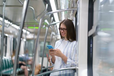 Yolcu genç bayan cep telefonu kullanıyor metro istasyonunda sosyal ağlarda sohbet ediyor.