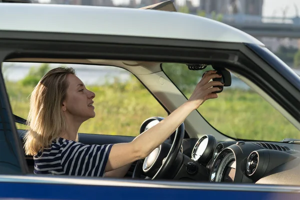 Szczęśliwa kobieta właściciel samochodu cieszyć jazdy na jazdę próbną dostosować tylne lusterko trzyma kierownicę — Zdjęcie stockowe