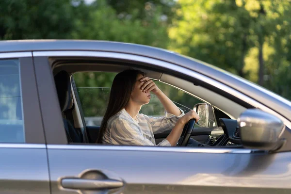 Стрессовая девушка с головной болью в машине. Разочарованная молодая женщина-водитель страдает от болезни — стоковое фото