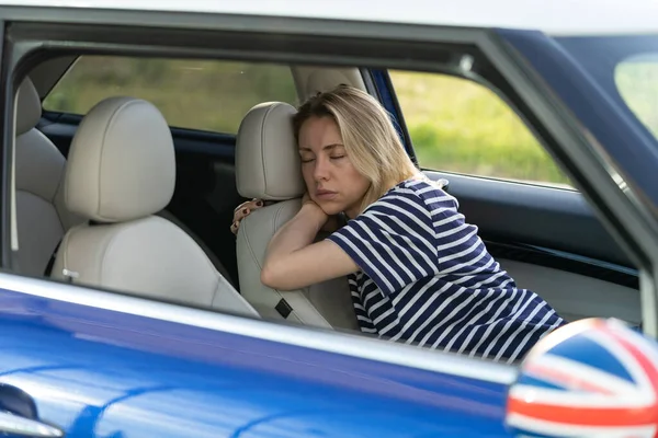 Tired woman sleep inside car on driver seat. Unhappy adult female fall asleep on parking after work
