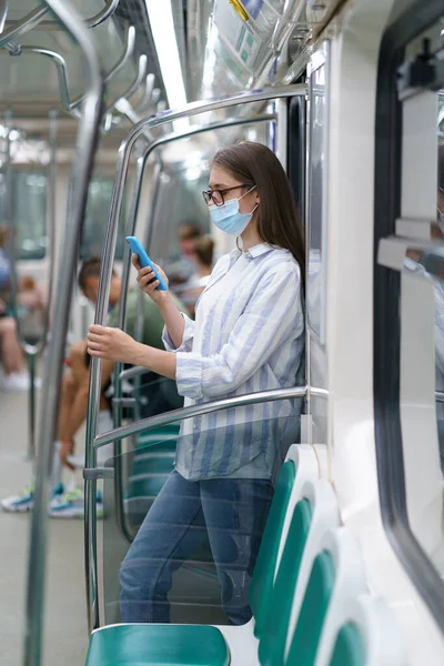 Metro arabasındaki kadın akıllı telefon kullanarak CV10 enfeksiyonundan korunmak için cerrahi maske takıyor. — Stok fotoğraf