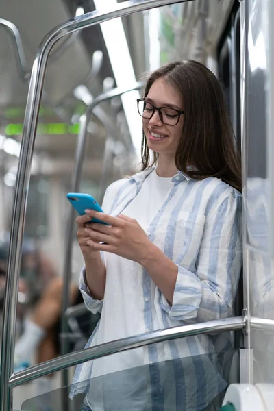 Passenger young woman using mobile smart phone chatting in social networks in subway train at metro — Stock Photo, Image