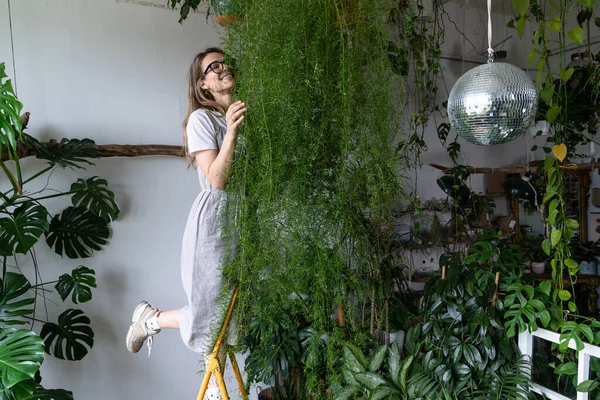 Mujer feliz jardinero abrazando espárragos planta de interior en casa. Jardín acogedor interior, concepto de pasatiempos — Foto de Stock