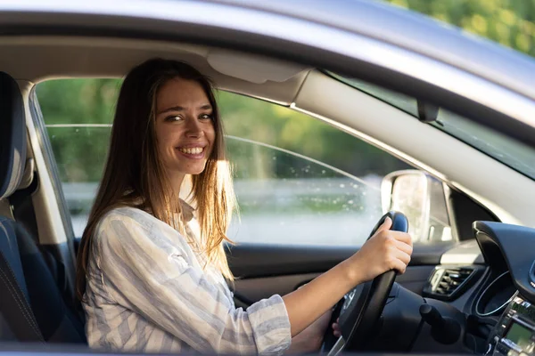 Молодая девушка сидит на водительском сиденье в новой машине улыбаясь держаться за руки на колесе счастливы получить водительские права — стоковое фото