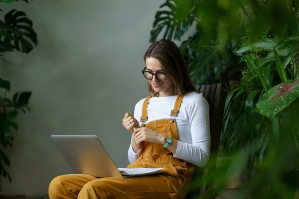 Ung flicka trädgårdsmästare student titta på webinar om hem trädgårdsskötsel, florist småföretag, krukväxt vård — Stockfoto