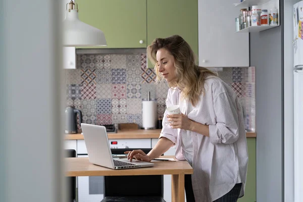 아침에 직장 여성이나 집에서 멀리 떨어져 일하는 근로자들 이 커피를 마시면서 노트북으로 이메일을 읽어 주는 모습 — 스톡 사진