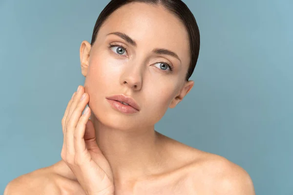 Ung kvinna med naturlig makeup, kammat hår, vidrör välvårdad ren hud i ansiktet. Skönhetsvård. — Stockfoto