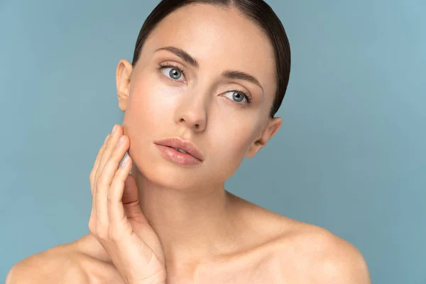 Giovane donna con trucco naturale, capelli pettinati, toccando la pelle pura ben curata sul viso. Cura di bellezza. — Foto Stock