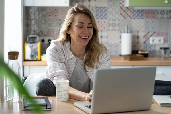 Захоплена жінка читає пропозицію роботи по електронній пошті від успішної компанії на блокування вдома на ноутбуці — стокове фото