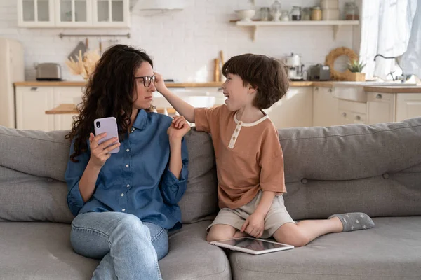 Aktif sıkılmış küçük oğul, genç anne iş kadınının dikkatini dağıtıyor. İnternetten akıllı telefondan ev telefonunda çalışıyor. — Stok fotoğraf