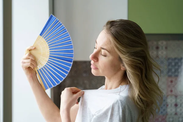 Mujer sobrecalentada en camiseta usando ventilador de onda sufren de sudoración por calor, se enfría, se siente lenta —  Fotos de Stock