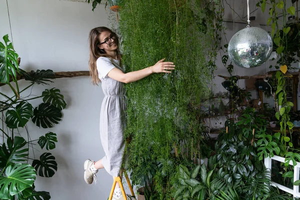 Mujer feliz jardinero abrazando espárragos planta de interior en casa. Jardín acogedor interior, concepto de pasatiempos — Foto de Stock