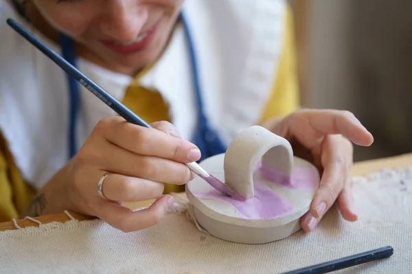 Художественный процесс в мастерской керамики: женщина-керамист рисует керамическую посуду в мастерской — стоковое фото