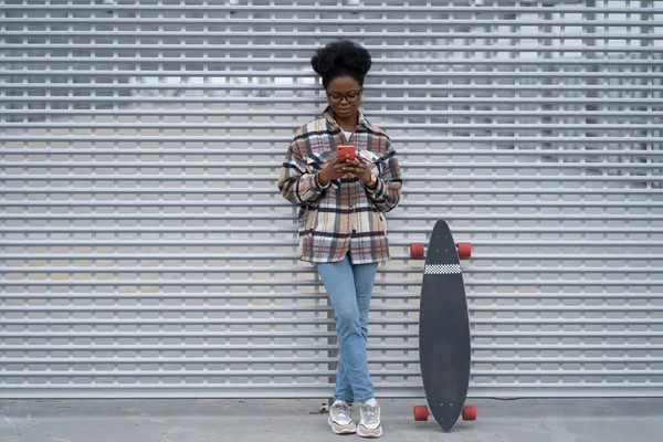 Молода афроамериканська дівчинка прокручує соціальні медіа у телефонній розмовній чаті, використовуючи бездротовий 5g інтернет. — стокове фото
