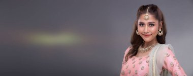 Hint güzel gözleri, mükemmel makyaj gelini, geleneksel etnik Pakistanlı gelinlik giymiş güzel bir kadının portresi, ağır mücevherler, gri arka plan fotokopi alanı afişi.