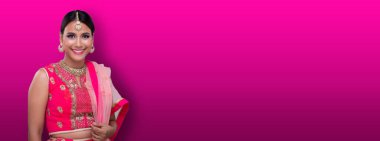Hint güzel gözleri, mükemmel makyaj gelini, geleneksel etnik Pakistanlı gelinlik giymiş güzel bir kadının portresi, ağır mücevherler, pembe arka plan fotokopi alanı afişi.