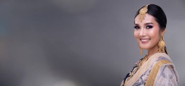 Hint güzel gözleri, mükemmel makyaj gelini, geleneksel etnik Pakistanlı gelinlik giymiş güzel bir kadının portresi, ağır mücevherler, gri arka plan afişi.