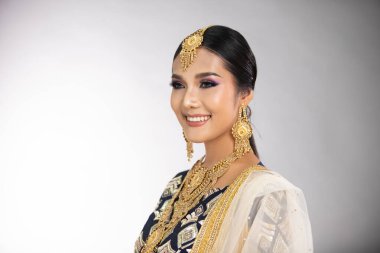 Hint güzel gözleri, mükemmel makyaj gelini, geleneksel etnik Pakistanlı gelinlik giymiş güzel bir kadının portresi, ağır mücevherler, gri arka plan afişi.