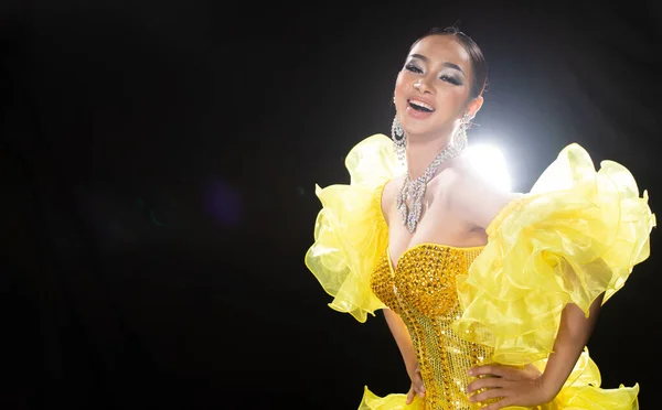 Half body portrait of Asian Transgender Woman in Cabaret Carnival Dancer Yellow Queen Dress Gown over Dark background as profile shooting copy space