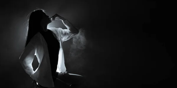 轮廓抽象的女性形象 表现出美丽的体形 身穿白衬衫 背光烟雾低曝光黑暗背景复制空间 — 图库照片