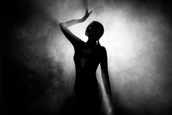 Silhouette abstract of woman body presents as Miss Beauty Queen Pageant Contest and win Diamond Crown. Backlit smoke low exposure dark background copy space
