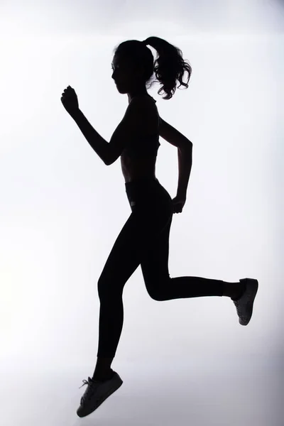 Silhouette slim body of Young Fitness Woman start running forward in full body length. High contrast white background copy space