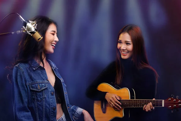 两名美丽的亚洲歌手在咖啡厅舞台上演唱和弹奏吉它 在音乐会期间 Lgbt情侣表达爱意 互相微笑 互相凝视 — 图库照片