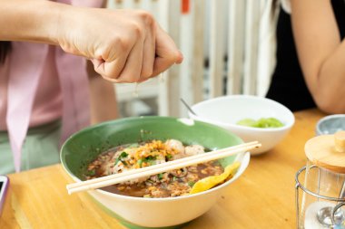 Lezzetli bir tat için baharatlı erişte çorbasına limonlu limonun yarısını sıkan Asyalı kadın.