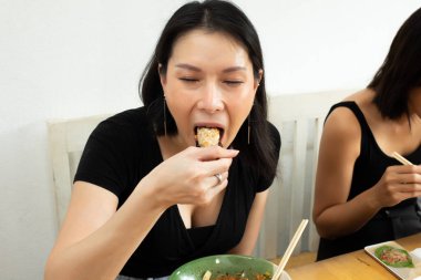 Transseksüel Asyalı Kadın acı soslu Wonton yer ve terden ağıza yapışır. Lezzetli yemekler yer, arka planı bulanıklaştırır.