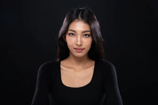 Fashion Beauty Woman has long straight black hair looks at camera and express feeling. Portrait of Asian girl strong face over black background, copy space