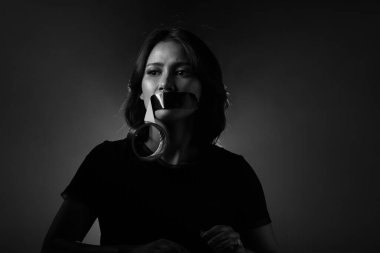 Asyalı Kadın toplumda adaletsizlik, güvensizlik ve yozlaşma hissediyor bu yüzden ağzını ördek bandıyla kapatıyor, tek kelime etmemek şartıyla. Koyu ton ortam kopyalama alanı