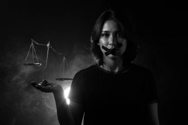 Asyalı Kadın toplumda adaletsizlik, güvensizlik ve yozlaşma hissediyor bu yüzden Mouth 'u ördek bandıyla kapatıyor ve tek kelime etmemek için dengesizlik ölçeği gösteriyor. Koyu ton ortam kopyalama alanı