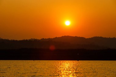 Orange Sun 'dan Sunset' e kadar dağın tepesinde ve uzak ağacın gölgesiyle nehri yansıtıyor. Huzurlu sakin yaşam arkaplan kopyalama alanı kavramı